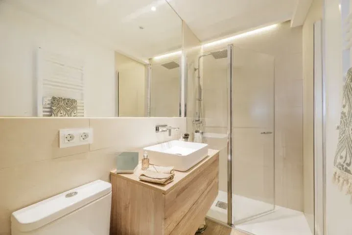 Salle de bain avec meuble-lavabo en bois et miroir sans cadre